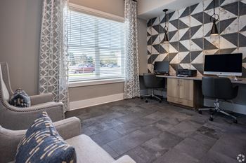 a room with a couch and chair and a desk with two computer monitors